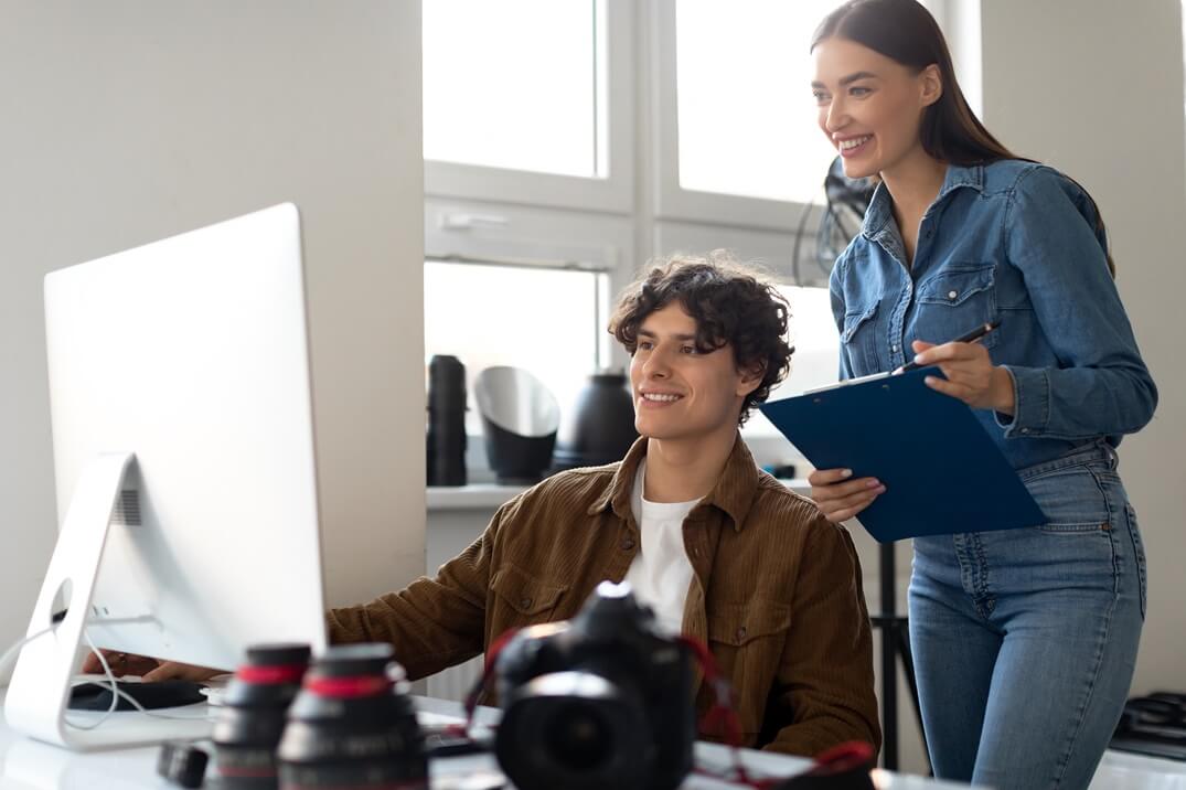 seoarng lelaki duduk dan perempuan berdiri sedang melihat laptop